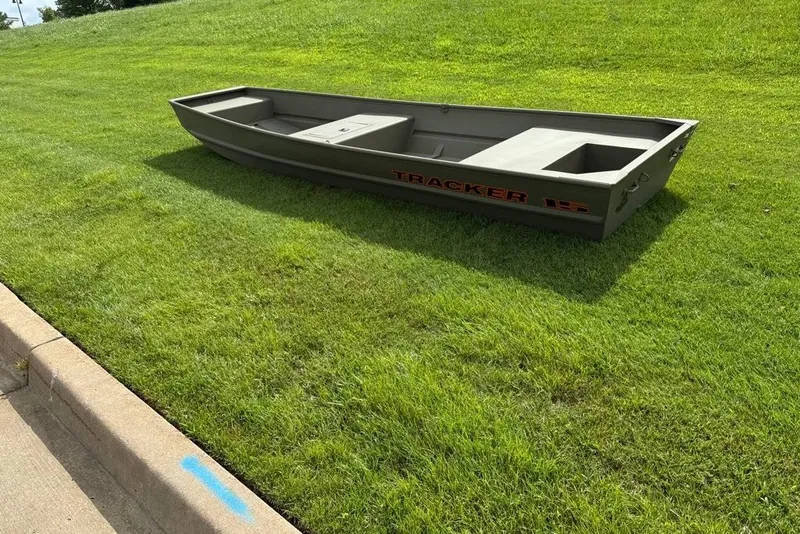 Slide: The Image of 2026 Tracker Grizzly 15 Jon boat on grassy lawn, showcasing its sturdy design. - 13