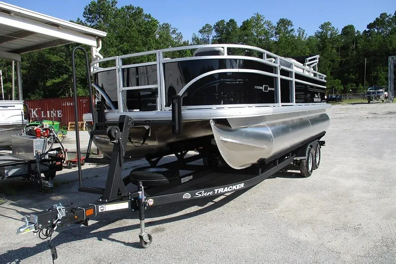 Slide: The Image of 2026 Sun Tracker Fishin' Barge 20 DLX pontoon boat on trailer, parked outdoors. - 3