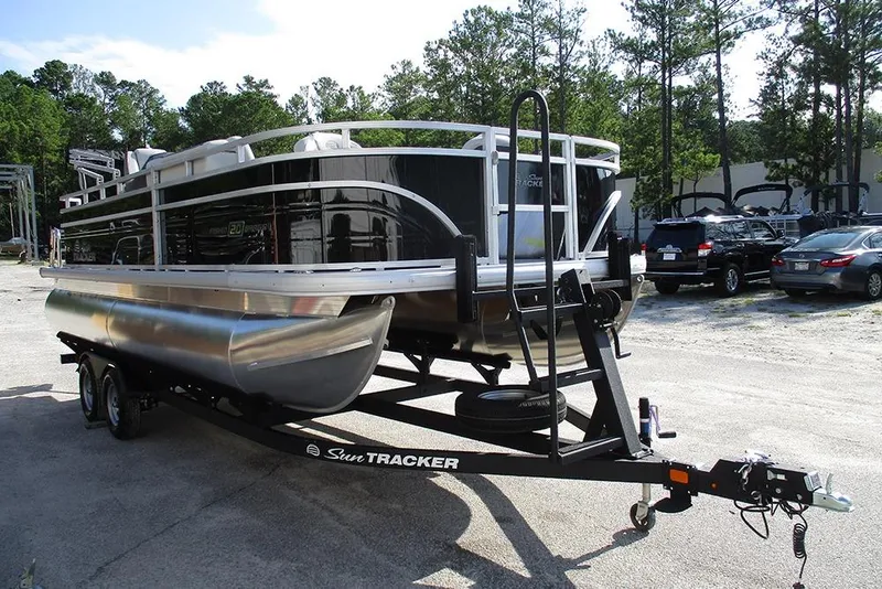 Slide: The Image of 2026 Sun Tracker Fishin' Barge 20 DLX pontoon boat on trailer, parked outdoors. - 5