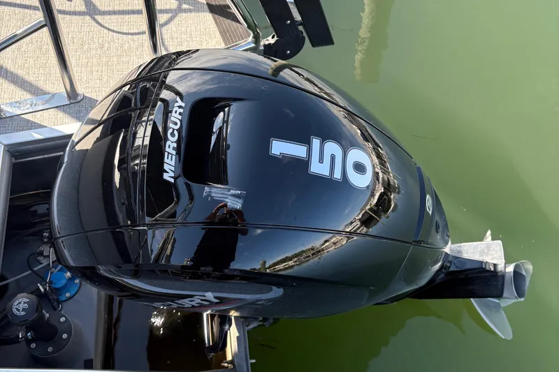Slide: The Image of Mercury 150 outboard motor on 2025 Harris Cruiser 230 pontoon boat, docked on calm water. - 11