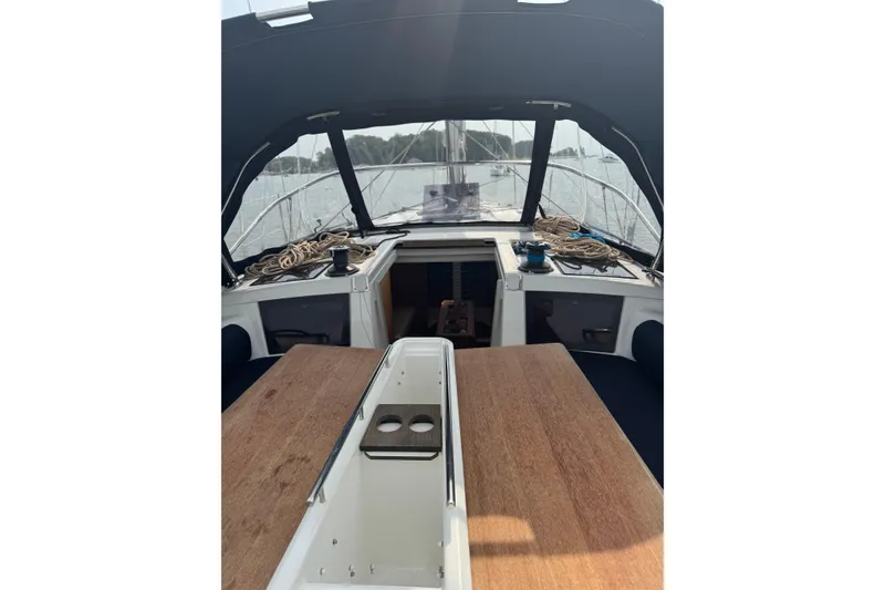 Slide: The Image of 2023 Dufour 37 yacht cockpit with wooden table and ropes, docked on a calm waterway. - 3