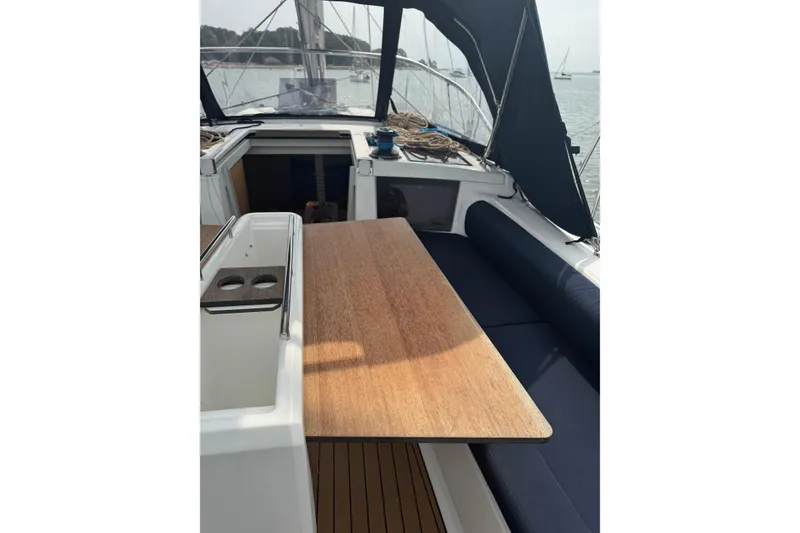 Slide: The Image of 2023 Dufour 37 yacht cockpit with wooden table and seating, docked in a serene harbor. - 7