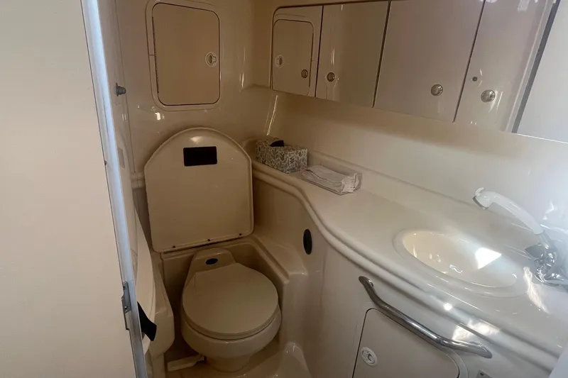 Slide: The Image of 2002 Sea Ray 320 Sundancer bathroom with toilet, sink, and storage cabinets. - 26