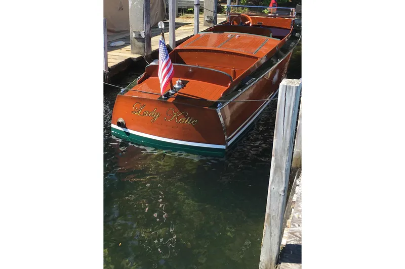 Slide: The Image of 1927 Chris-Craft Lancer 22 boat named "Lady Katie" docked with American flag. - 2
