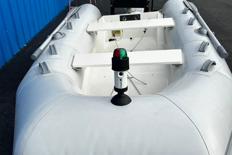 Slide: The Image of 2019 Brig Falcon 300 inflatable boat with navigation light, docked near blue wall. - 12