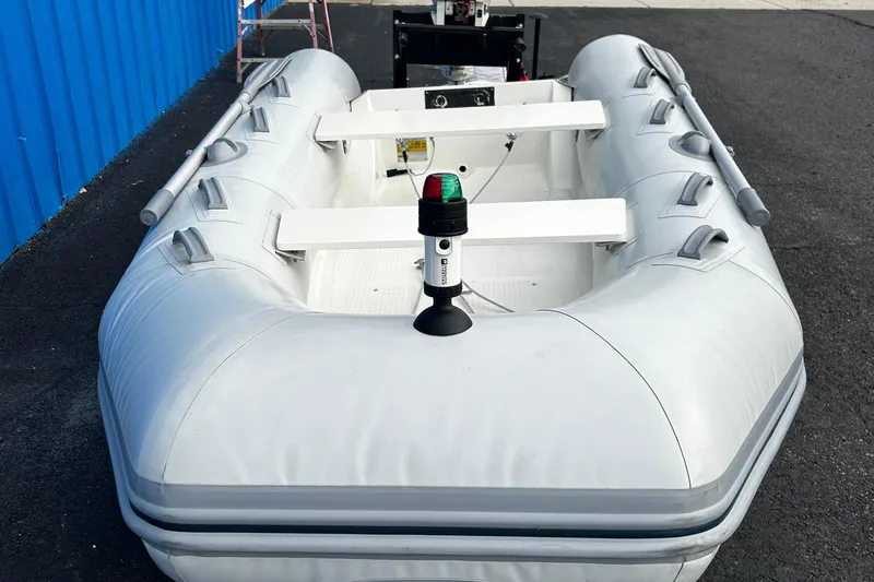 Slide: The Image of 2019 Brig Falcon 300 inflatable boat with oars and navigation light, docked on asphalt. - 13