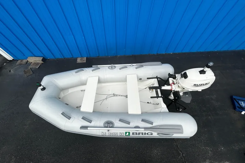 Slide: The Image of 2019 Brig Falcon 300 inflatable boat with Suzuki outboard motor, parked on pavement. - 3