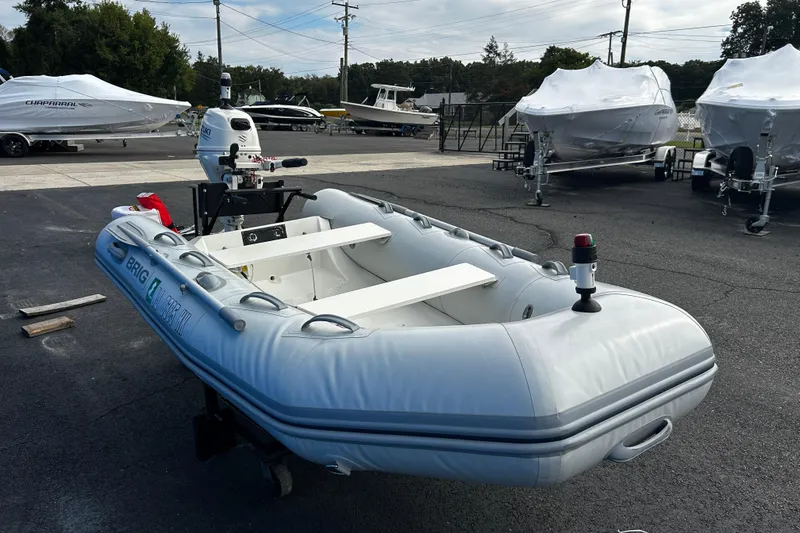 Slide: The Image of 2019 Brig Falcon 300 inflatable boat with outboard motor, displayed outdoors. - 8