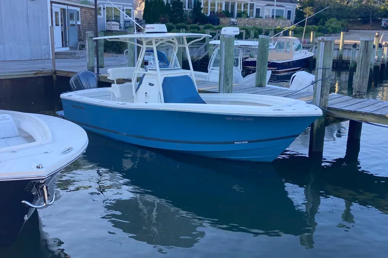 The Image of 2017 Regulator 23 Forward Seating boat docked in a marina, blue hull, calm water. - 0