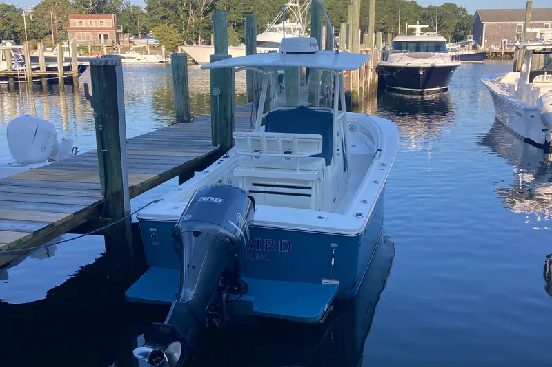 Slide: The Image of 2017 Regulator 23 Forward Seating boat docked in a marina, featuring a powerful outboard motor. - 2