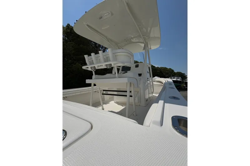 Slide: The Image of 2017 Regulator 23 Forward Seating boat with white interior and T-top under clear sky. - 21