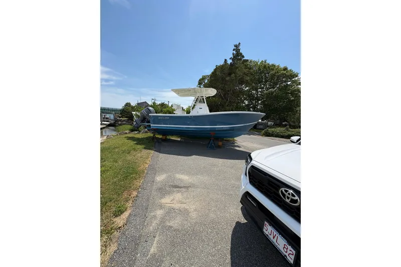 Slide: The Image of 2017 Regulator 23 Forward Seating boat on a driveway, sunny day, trees in background. - 5