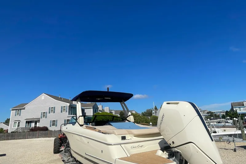 Slide: The Image of 2026 Chris-Craft Sportster 28 boat with Mercury engine, parked outdoors under blue sky. - 4