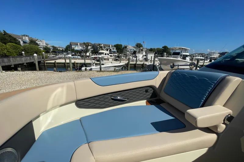 Slide: The Image of 2026 Chris-Craft Sportster 28 boat interior with blue and white seating, docked near waterfront homes. - 51