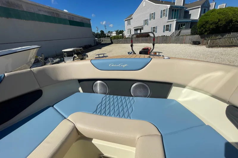 Slide: The Image of 2026 Chris-Craft Sportster 28 boat interior with blue and beige seating, parked outdoors. - 52