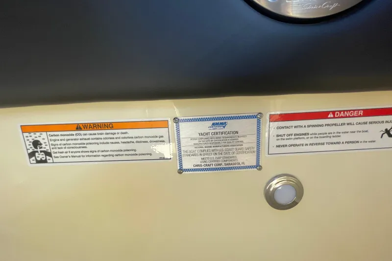 Slide: The Image of Warning and certification labels on 2026 Chris-Craft Sportster 28 boat dashboard. - 64