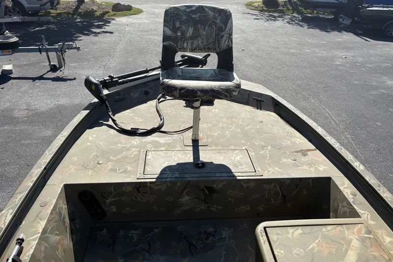 Slide: The Image of 2024 Tracker Grizzly 1754 SC boat with camouflage seating and deck, parked outdoors. - 14