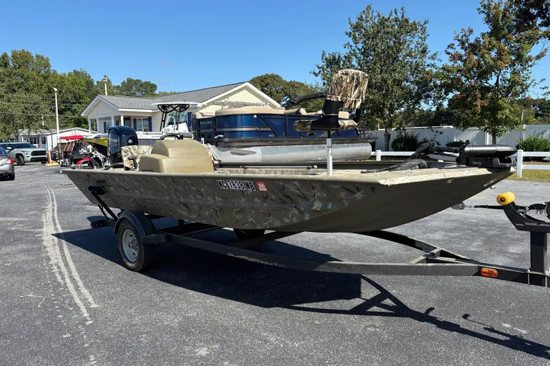 Slide: The Image of 2024 Tracker Grizzly 1754 SC boat on trailer, parked outdoors near residential area. - 17