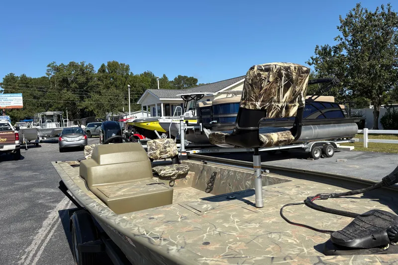 Slide: The Image of 2024 Tracker Grizzly 1754 SC boat with camouflage seats in a dealership lot. - 19