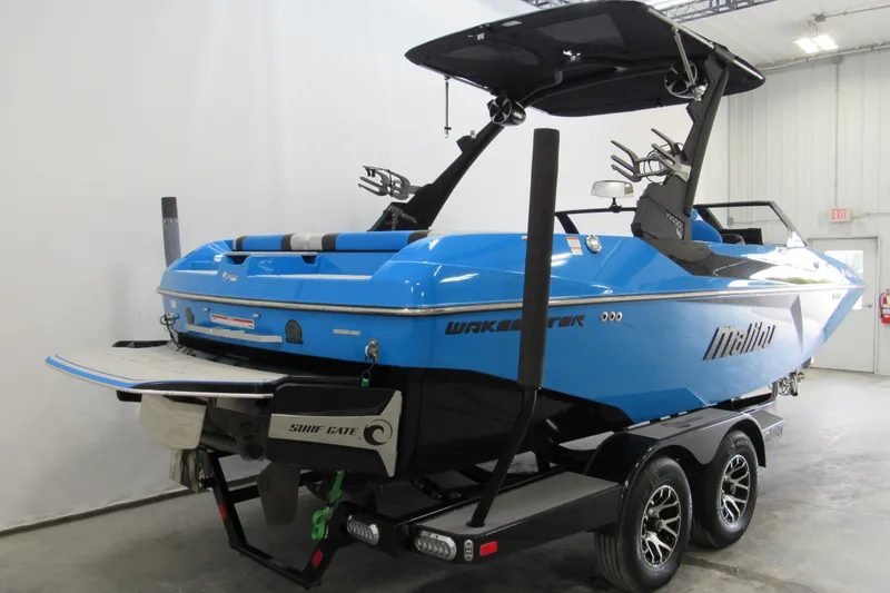 Slide: The Image of 2021 Malibu Wakesetter 21 MLX boat in blue, displayed indoors on a trailer. - 2