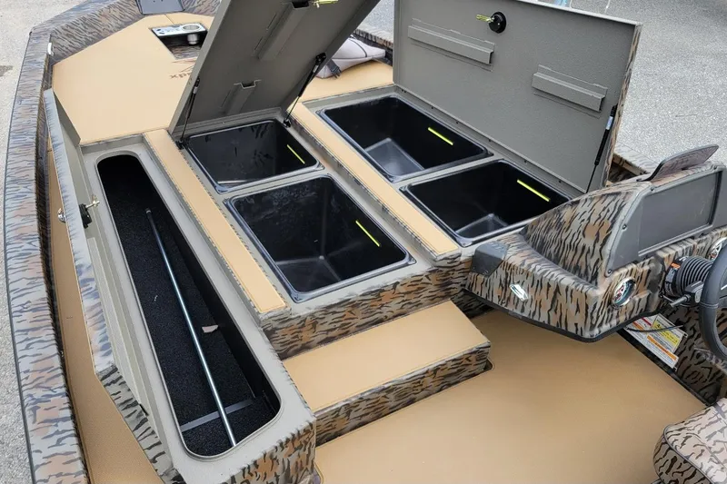 Slide: The Image of 2026 Xpress H20 Bass boat interior with open storage compartments and camouflage design. - 3