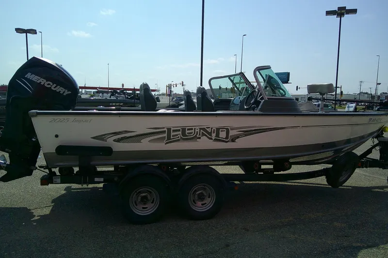 Slide: The Image of 2016 Lund 2025 Impact boat on trailer with Mercury outboard motor in parking lot. - 4