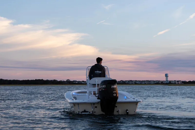 Slide: The Image of Man steering 2016 Intruder 198 Tunnel Drive boat at sunset on calm water. - 11