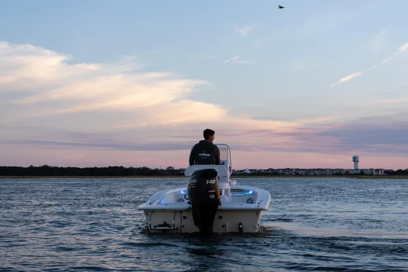 Slide: The Image of Man on 2016 Intruder 198 Tunnel Drive boat at sunset on calm water. - 12