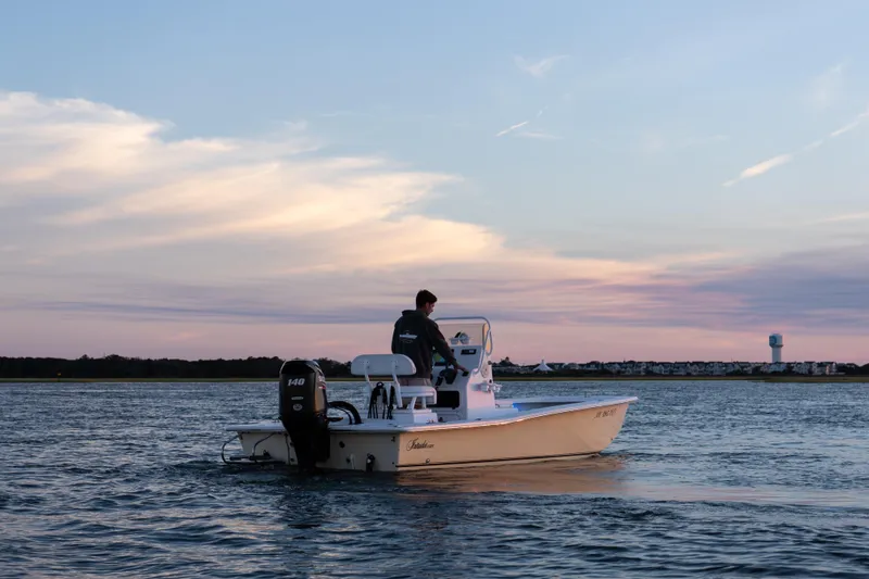 Slide: The Image of Man on 2016 Intruder 198 Tunnel Drive boat at sunset on calm water. - 13