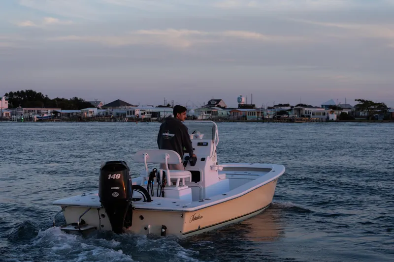 Slide: The Image of Man steering 2016 Intruder 198 Tunnel Drive boat on calm water at sunset. - 7