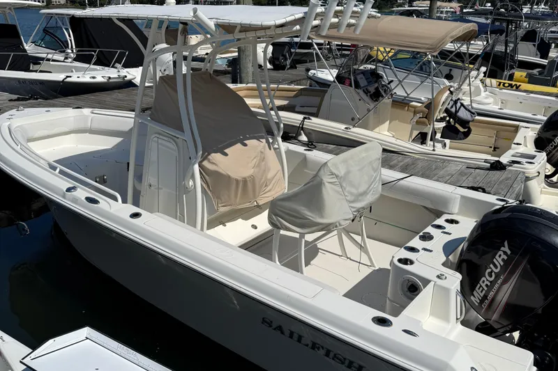 Slide: The Image of 2015 Sailfish 220 CC boat docked, featuring Mercury outboard engine and covered seating. - 3