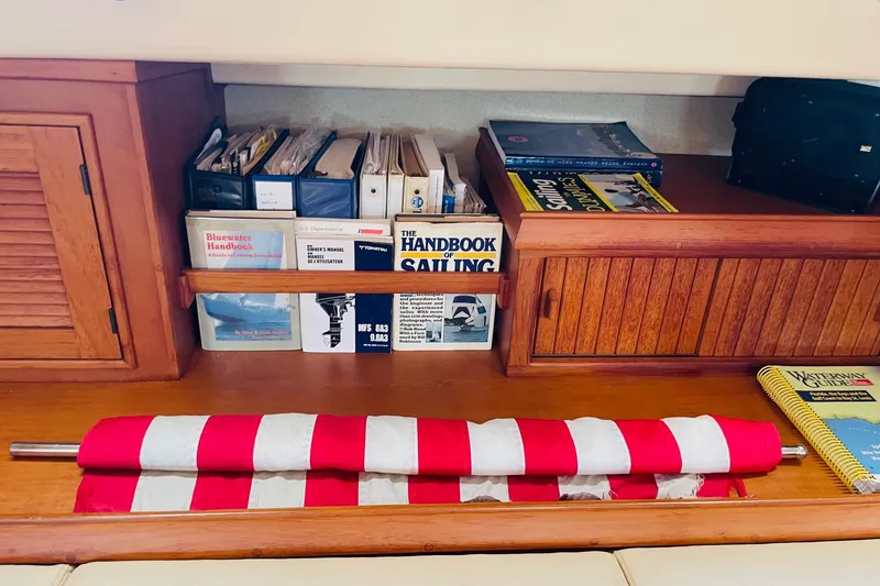 Slide: The Image of Nautical bookshelf on 2002 Island Packet 420 yacht with sailing guides and folded flag. - 40