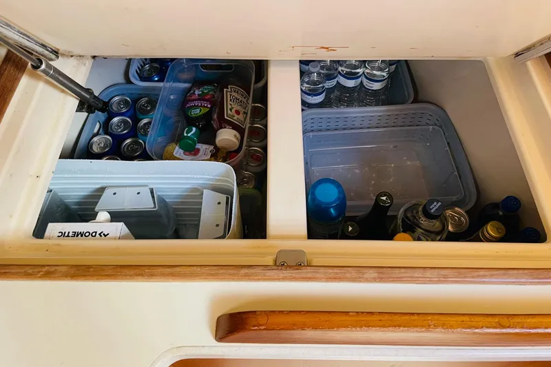 Slide: The Image of Storage compartment on 2002 Island Packet 420 yacht, stocked with beverages and condiments. - 59