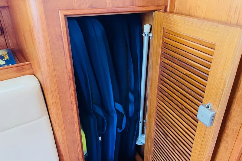 Slide: The Image of Wooden cabinet with blue life jackets inside, on a 2002 Island Packet 420 yacht. - 71