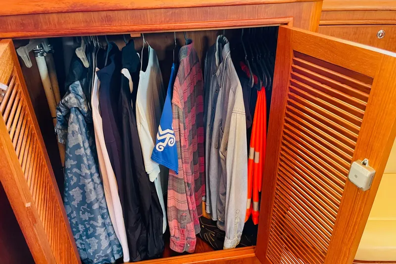 Slide: The Image of Clothes neatly hanging in a wooden closet on a 2002 Island Packet 420 yacht. - 74