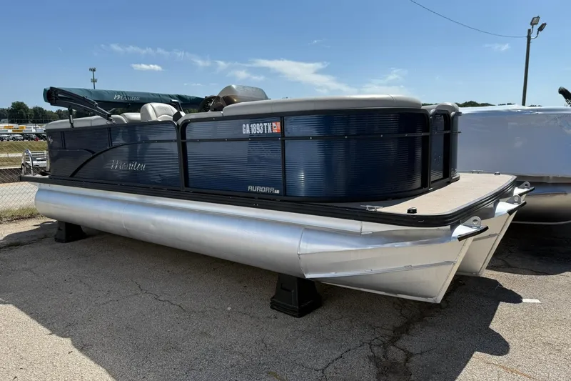Slide: The Image of 2020 Manitou 21 Aurora LE pontoon boat on display in a parking lot. - 0
