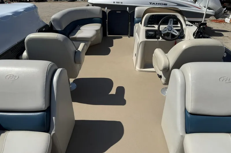 Slide: The Image of 2020 Manitou 21 Aurora LE pontoon boat interior with beige and blue seating. - 4