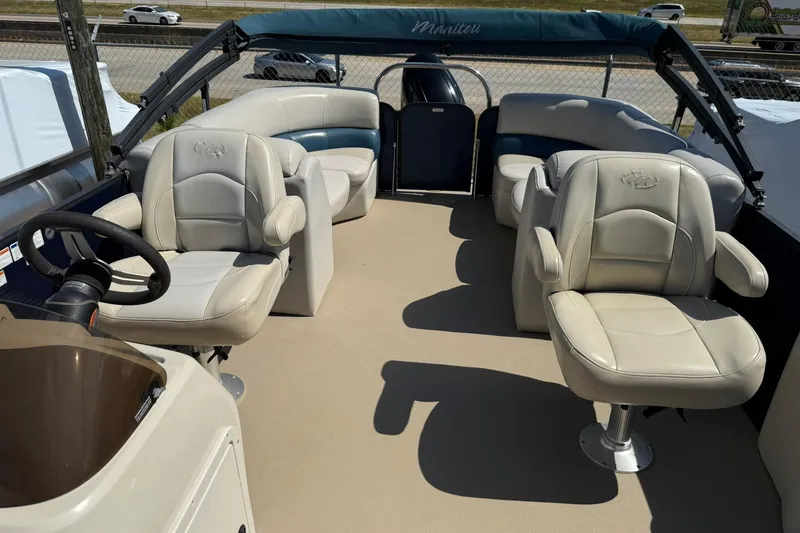 Slide: The Image of 2020 Manitou 21 Aurora LE pontoon boat interior with plush seating and steering console. - 5