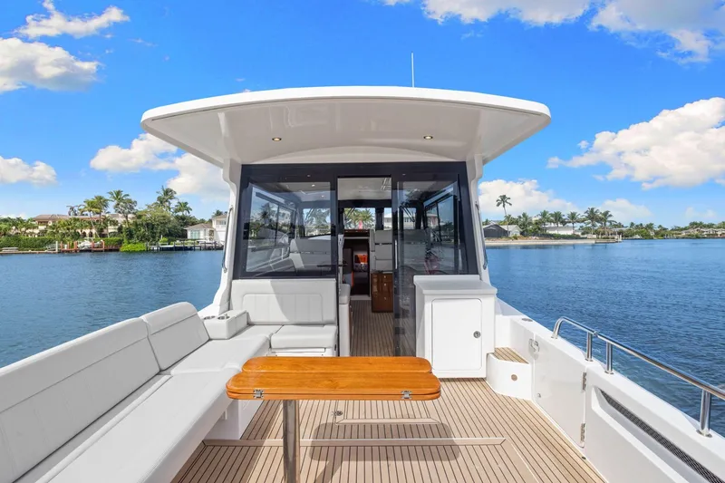 Slide: The Image of 2024 MJM 42 yacht with spacious deck, elegant seating, and scenic waterfront view. - 11