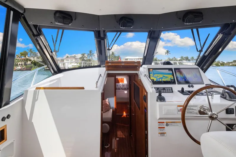 Slide: The Image of 2024 MJM 42 yacht cockpit with navigation screens, steering wheel, and scenic water view. - 24