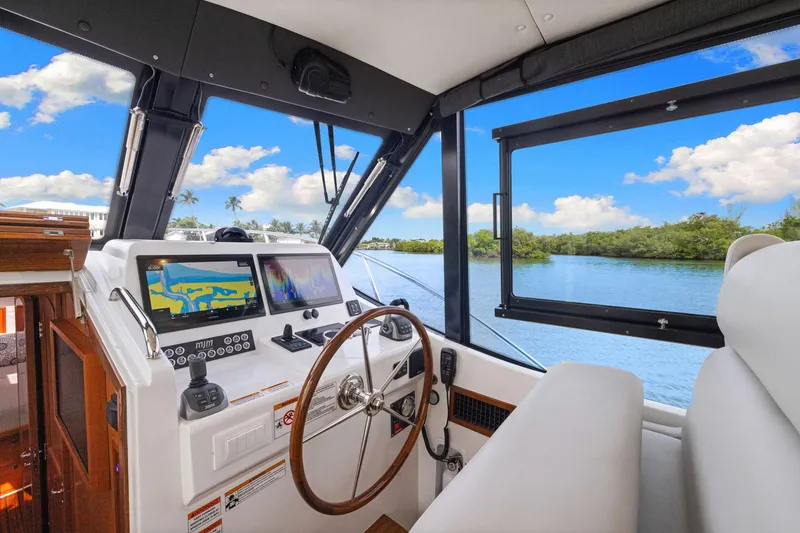 Slide: The Image of 2024 MJM 42 yacht helm with navigation screens, steering wheel, and scenic water view. - 27