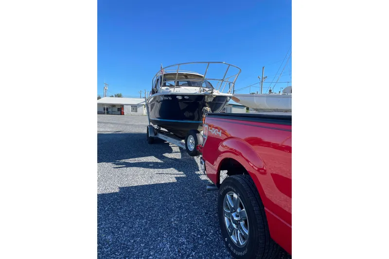 Slide: The Image of 2016 Cutwater C-24 Coupe boat on trailer, towed by red truck in sunny lot. - 12