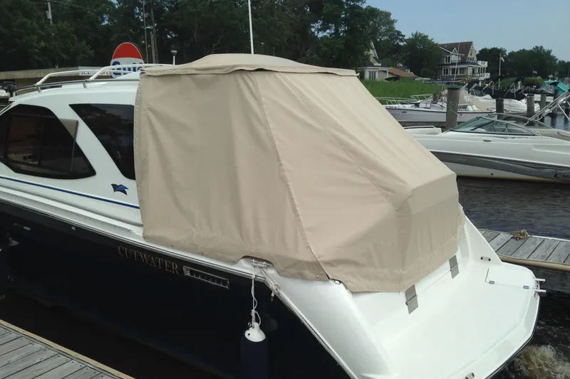 Slide: The Image of 2016 Cutwater C-24 Coupe with beige cover docked at marina. - 3