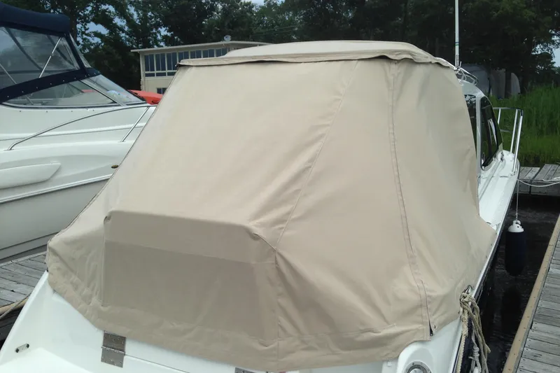 Slide: The Image of 2016 Cutwater C-24 Coupe with beige cover docked at marina. - 4