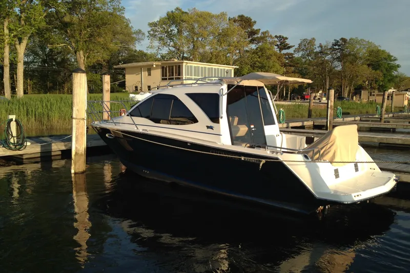 Slide: The Image of 2016 Cutwater C-24 Coupe docked at a serene marina, surrounded by lush greenery. - 8