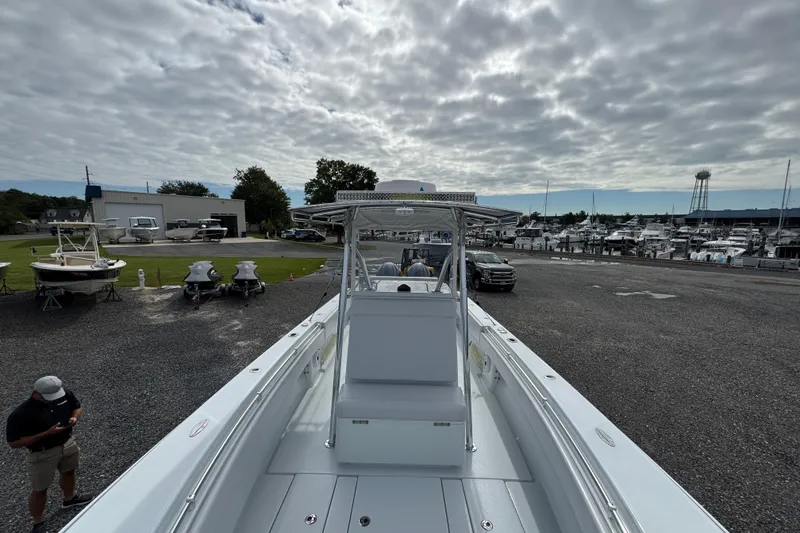 Slide: The Image of 2022 Contender 32 ST boat at marina, cloudy sky, parked vehicles, and boats in background. - 10