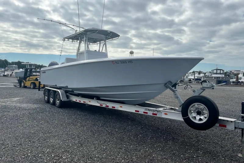 Slide: The Image of 2022 Contender 32 ST boat on trailer, parked in marina under cloudy sky. - 3