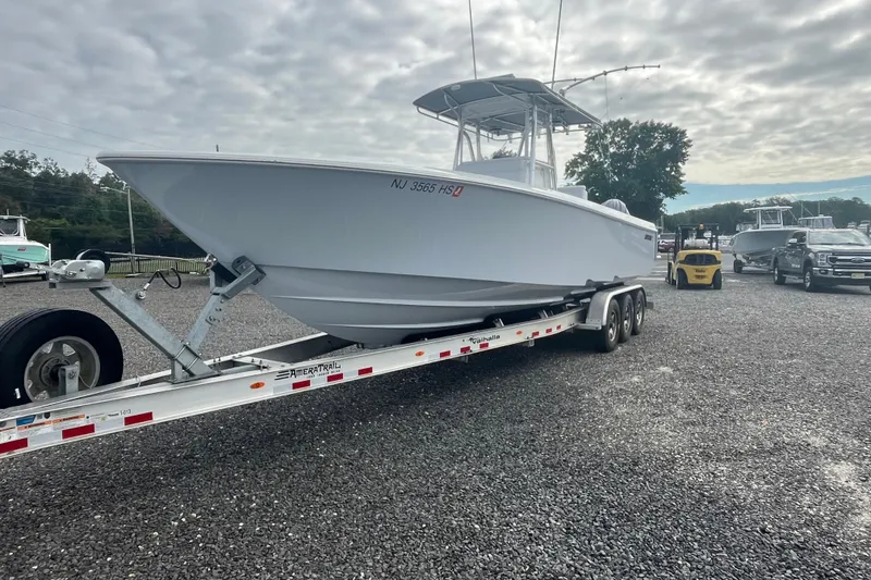 Slide: The Image of 2022 Contender 32 ST boat on trailer, parked on gravel lot under cloudy sky. - 4