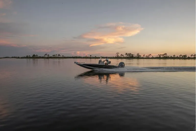 Slide: The Image of 2026 Xpress H20B boat cruising on a serene lake at sunset. - 1