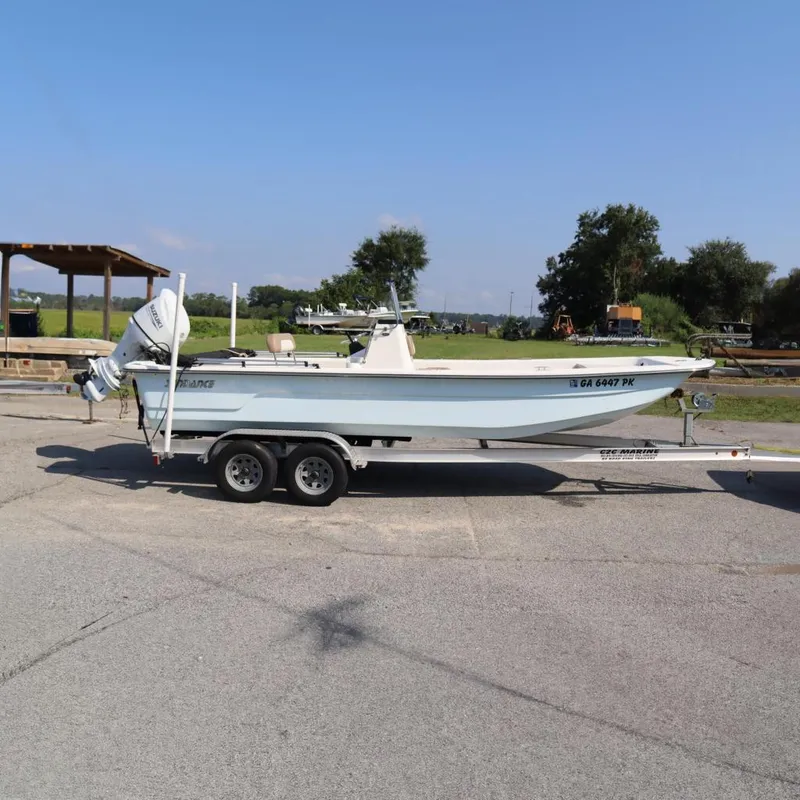 The Image of 2022 Sundance DX22 boat on trailer in sunny outdoor setting. - 0